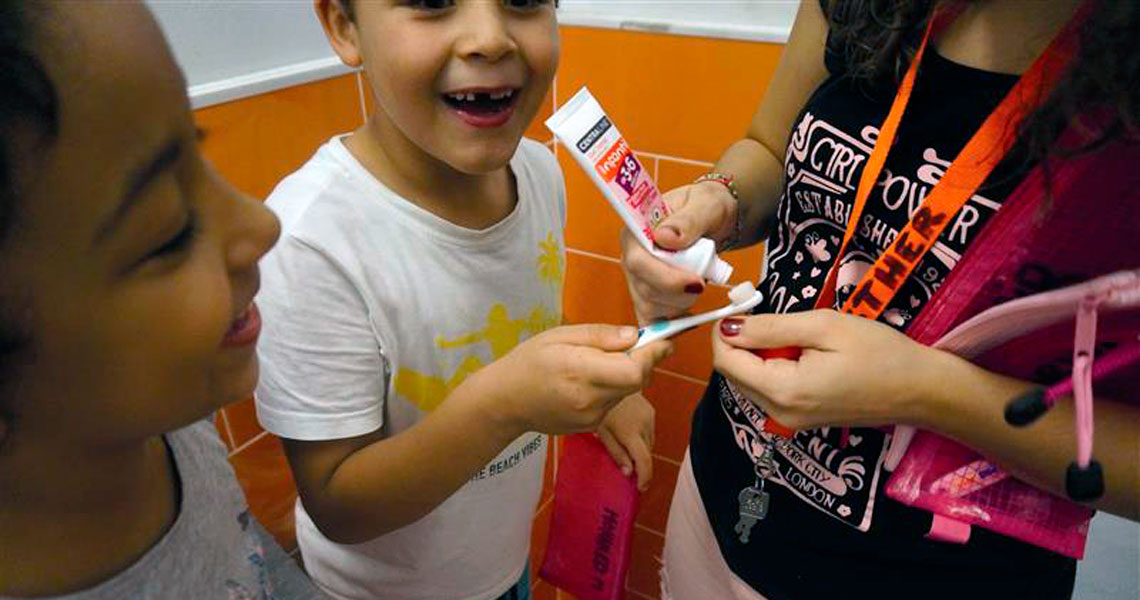 Infants amb educadora preparant-se per rentar-se les dents