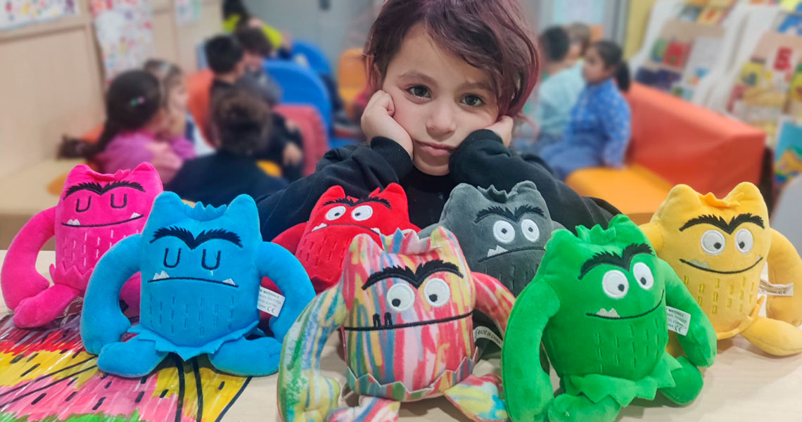 Niño con peluches del monstruo de colores en un centro socioeducativo