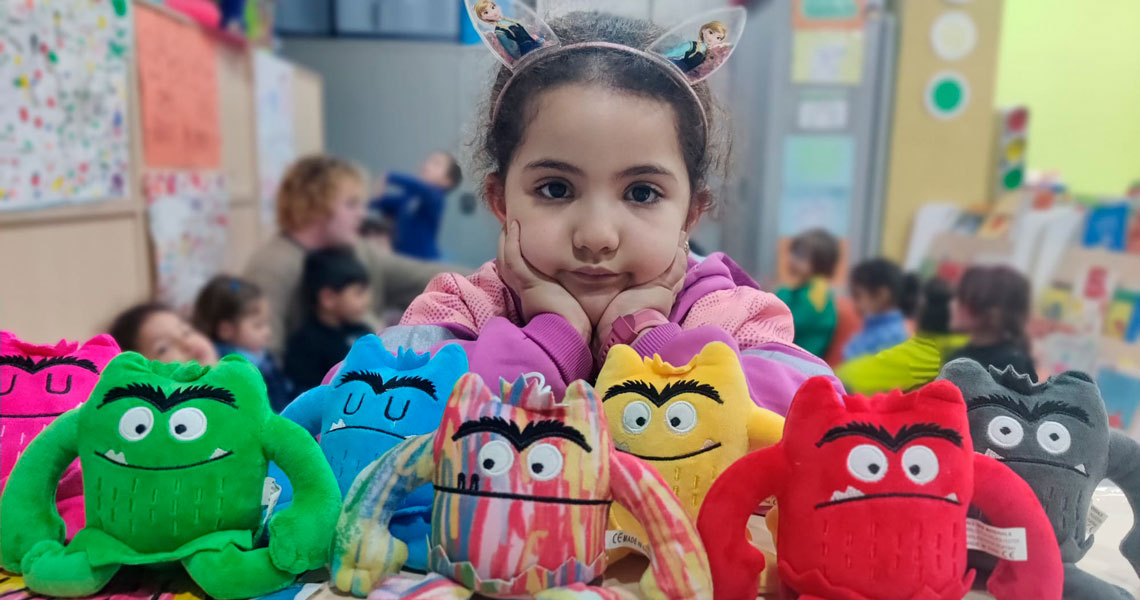 Niña con peluches del monstruo de colores en un centro socioeducativo
