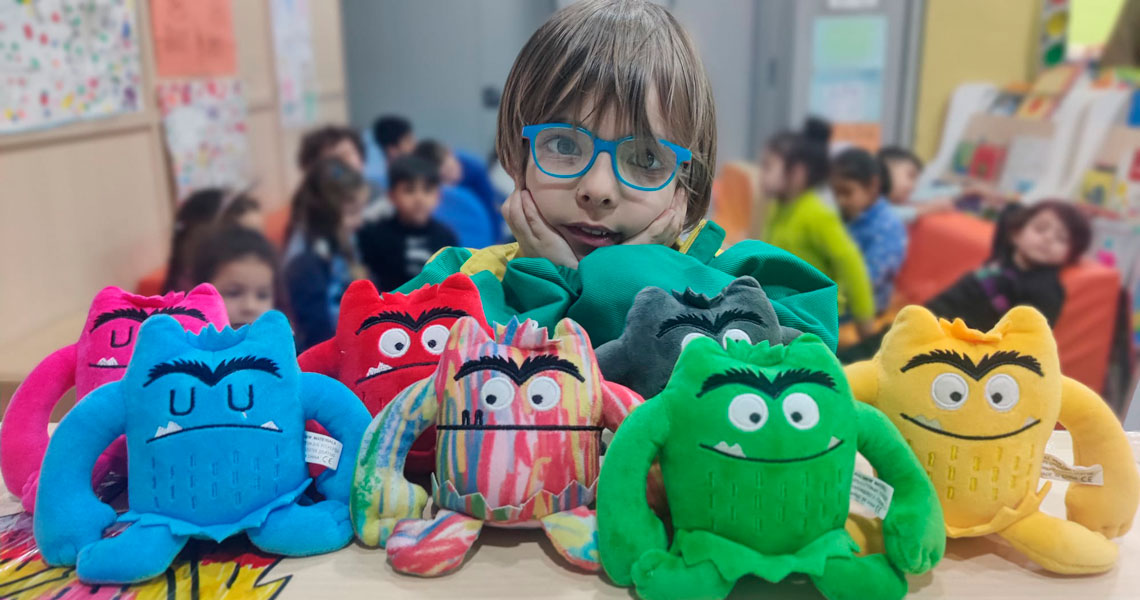 Niño con peluches del monstruo de colores en un centro socioeducativo