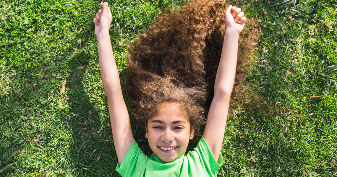 Niña feliz estirada en la hierba