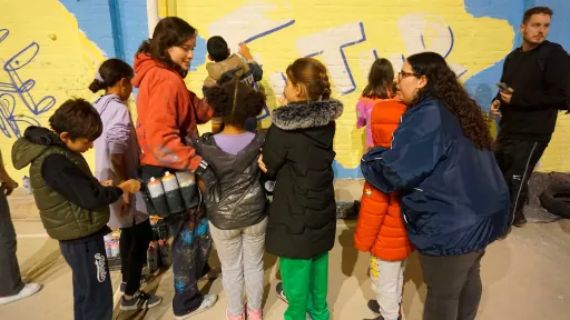 Infants pintant un mur a un centre socioeducatiu