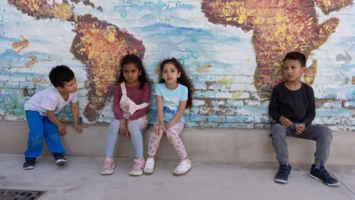 Infants davant un mural d'un mapamundi al centre socioeducatiu Poblenou