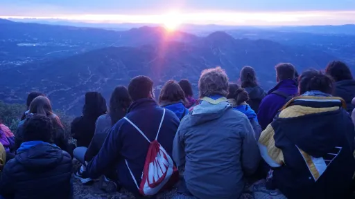 Joves a la muntanya veient la posta de sol