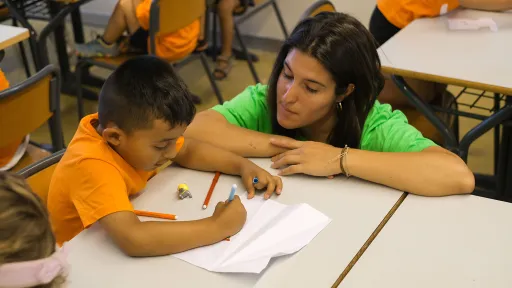 Nen dibuixant amb una monitora a l'aula