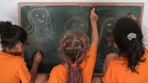 Nenes dibuixant a una pissarra en un centre socioeducatiu