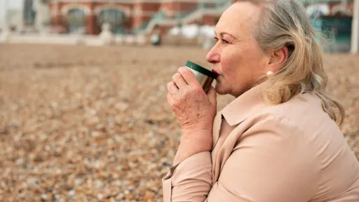 Dona gran amb un café a una platja