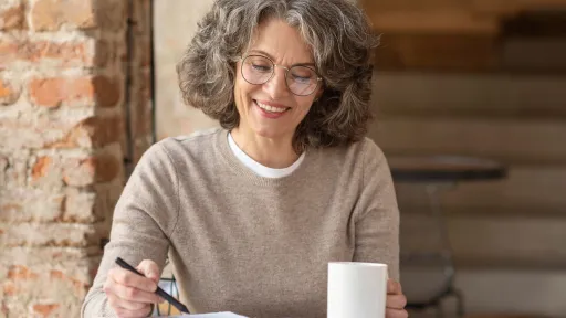 Dona gran treballant en una taula amb un café
