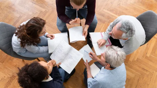 Grup de persones amb documents reunides en cercle