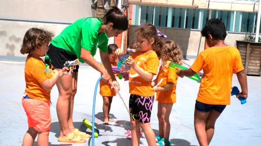 Infants amb monitora fent jocs d'aigua a un casal d'estiu
