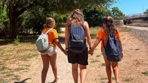 Monitora de la ma amb dos infants a una casa de colònies de les Illes Balears
