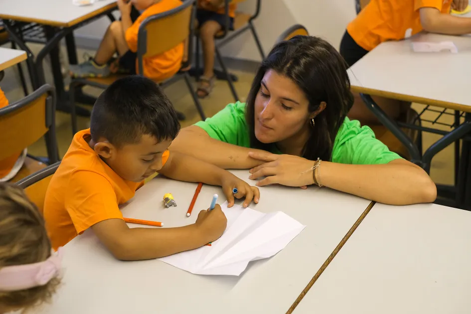 Nen dibuixant amb una monitora a l'aula
