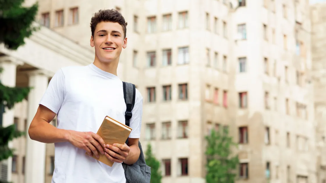Estudiant al campus amb un llibre a la ma
