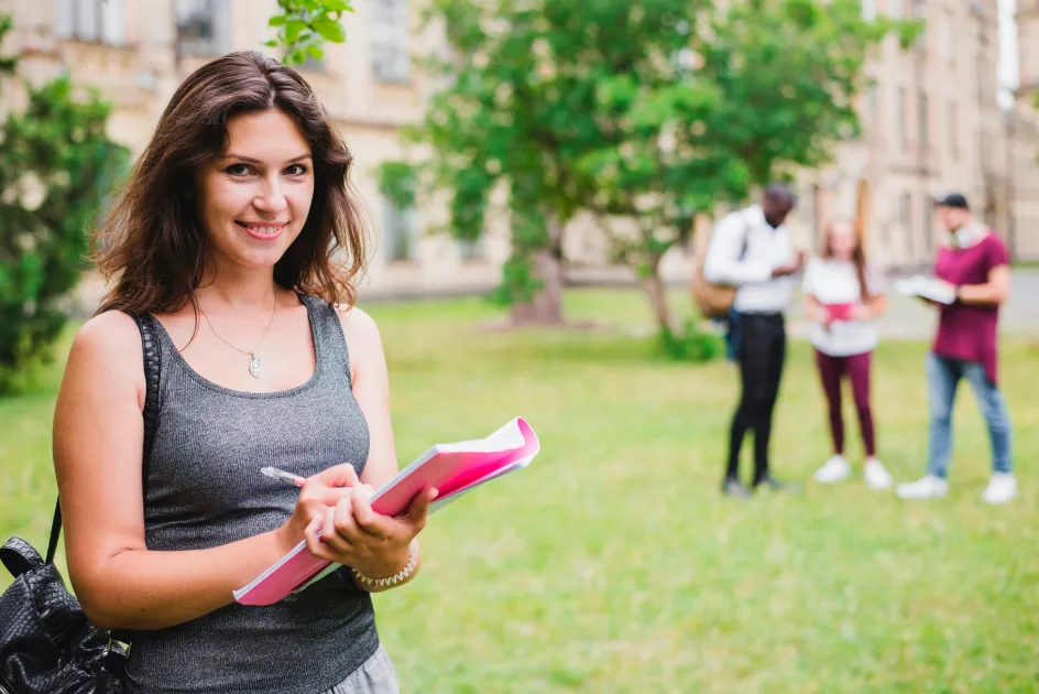 Estudiante con sus apuntes en un campus universitario