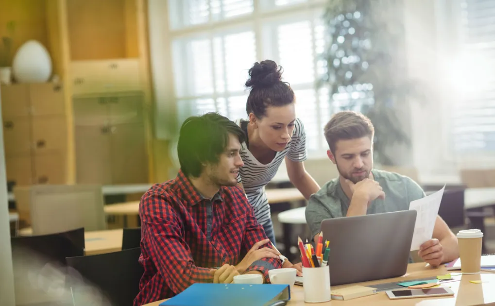 Persones joves mirant un portatil que està sobre una taula