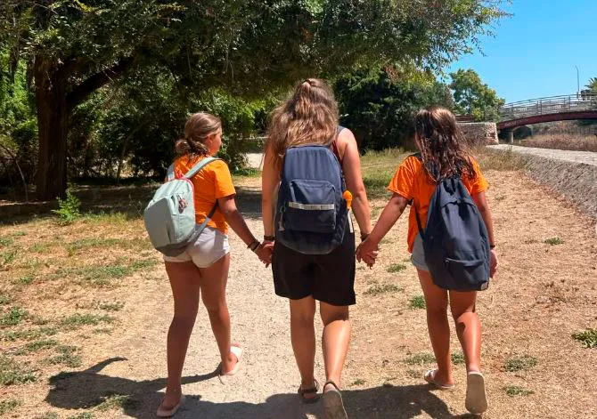 Monitora de la ma amb dos infants a una casa de colònies de les Illes Balears