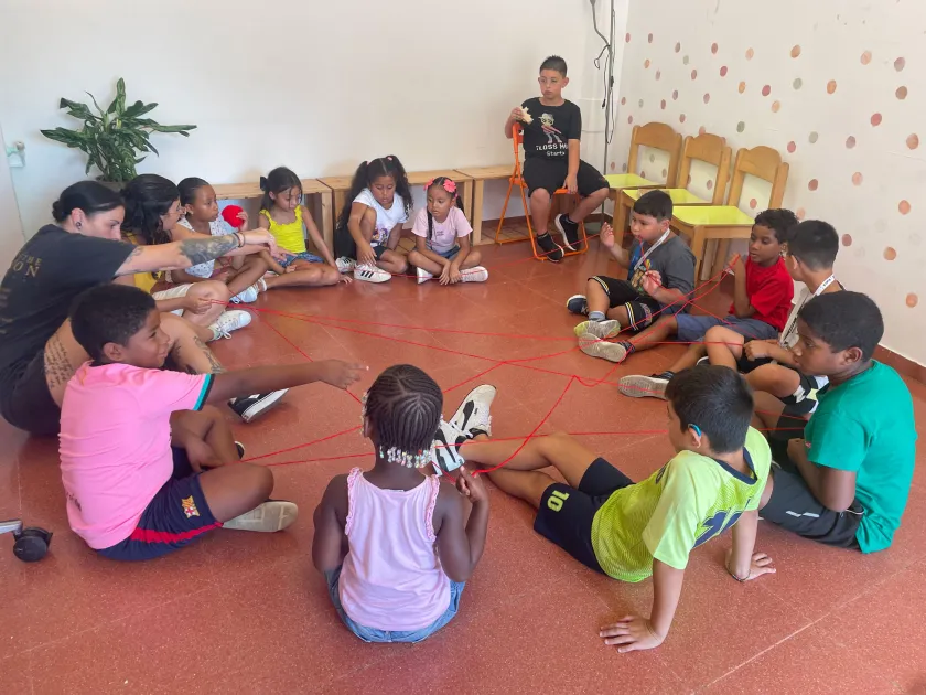 Infants i monitora jugant en rotllana a un casal social d'estiu a Torre Baró