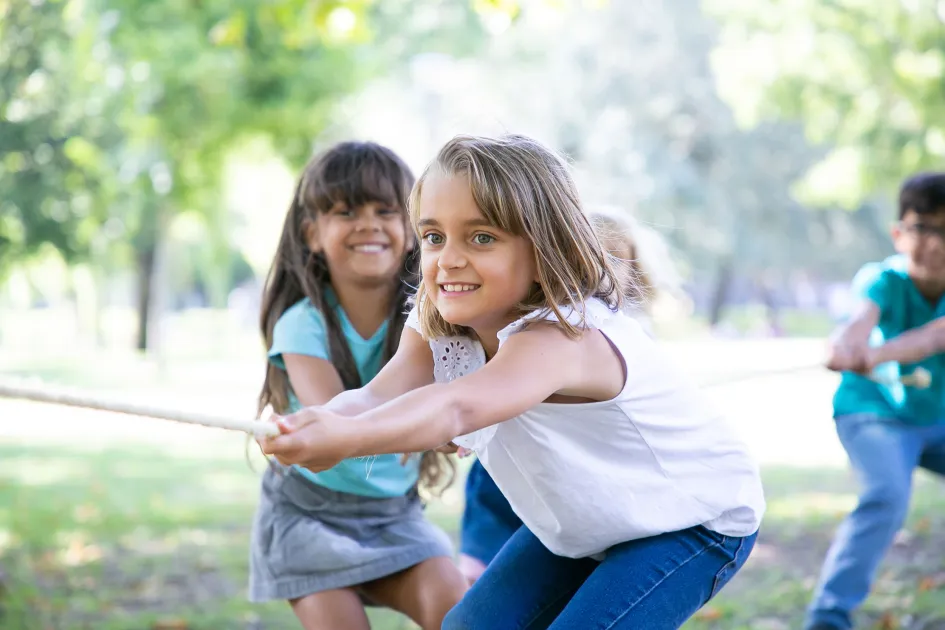 Infants en un parc jugant al joc de la corda