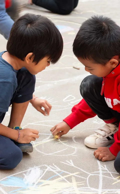 Nens al pati d'un centre socioeducatiu dibuixant amb guix